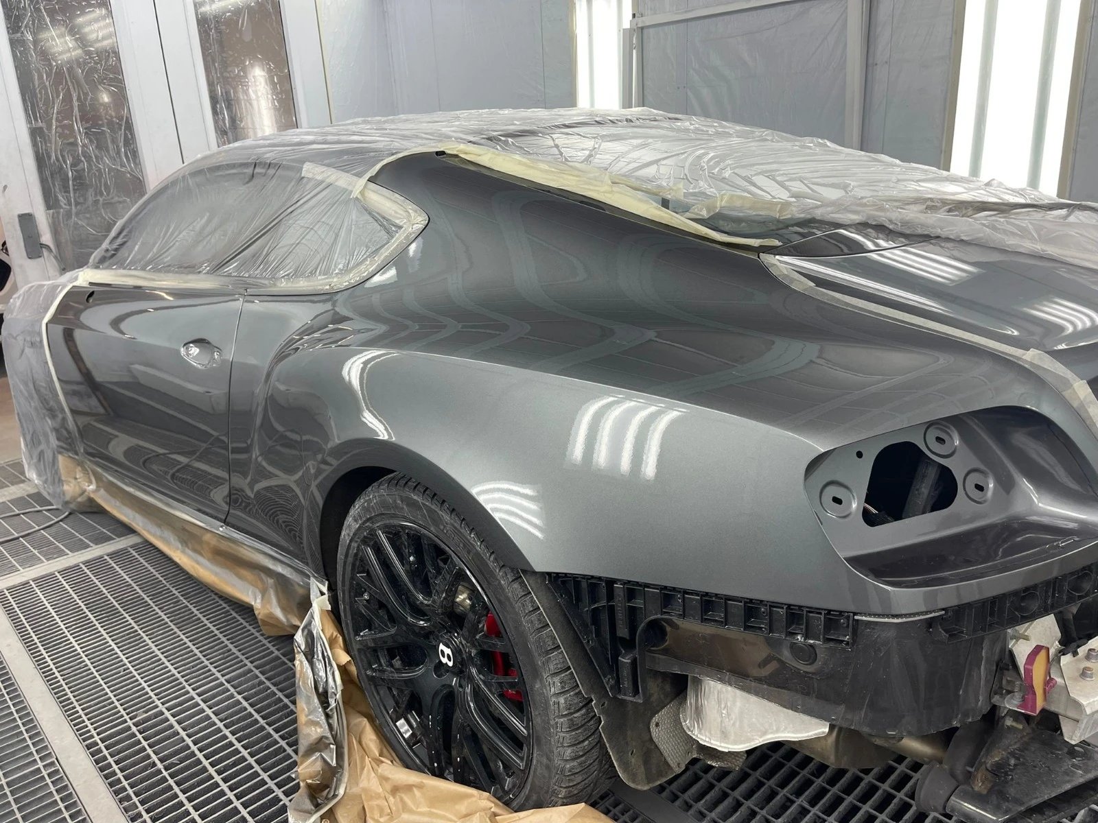Bentley Continental GT dans la cabine de peinture de l’atelier, éléments masqués et panneau fraîchement verni